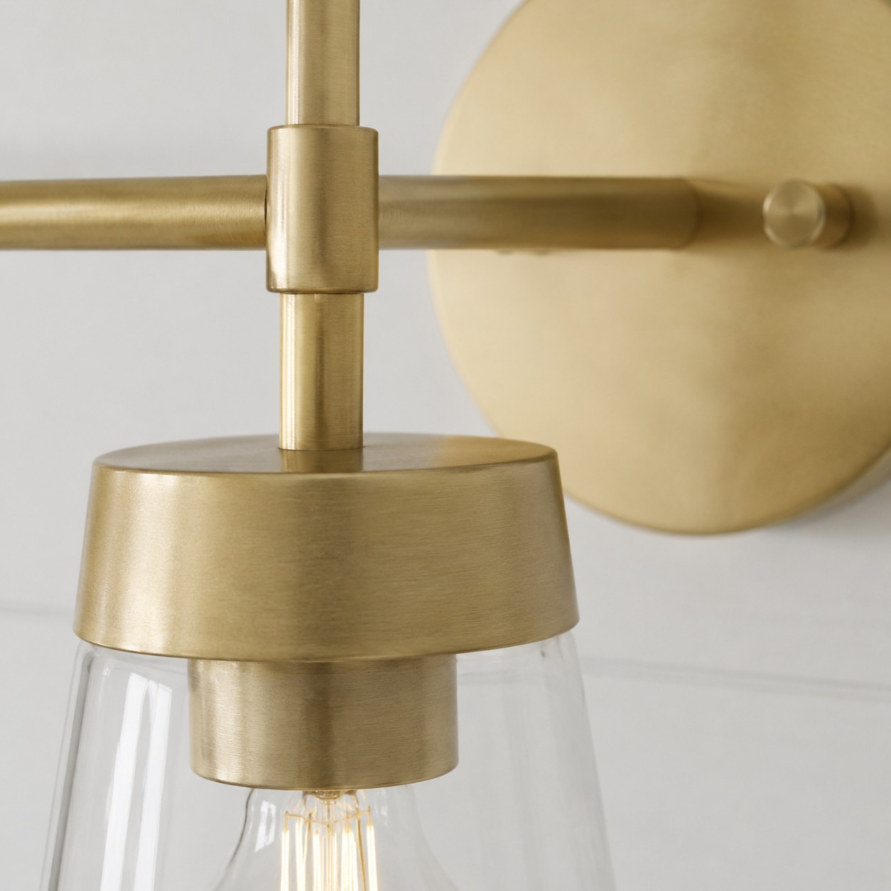 Close view of brushed brass joint and clear glass shade
