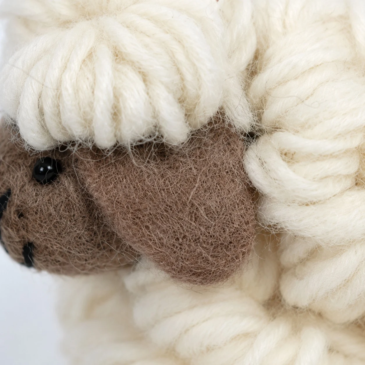 close detail of brown felt sheep face and cream wool fleece