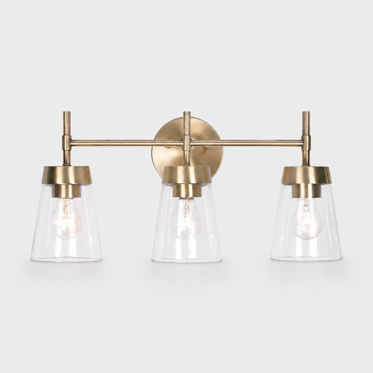 Brushed brass three-light vanity wall fixture on white background
