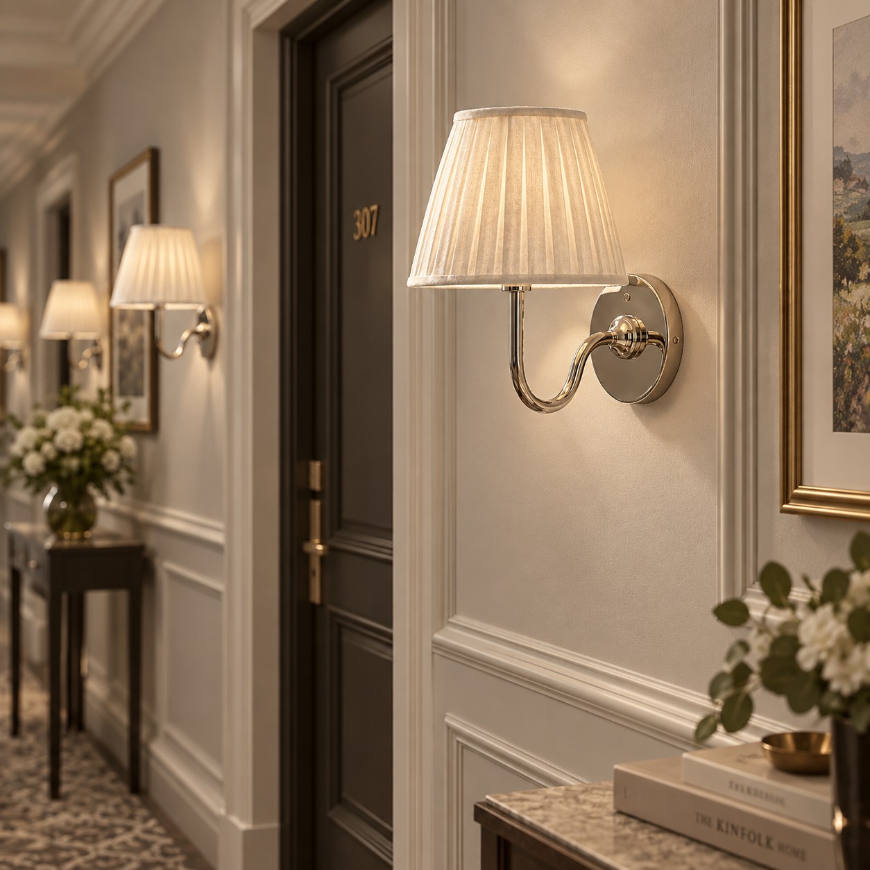 Row of chrome Tansy sconces lighting a paneled hallway
