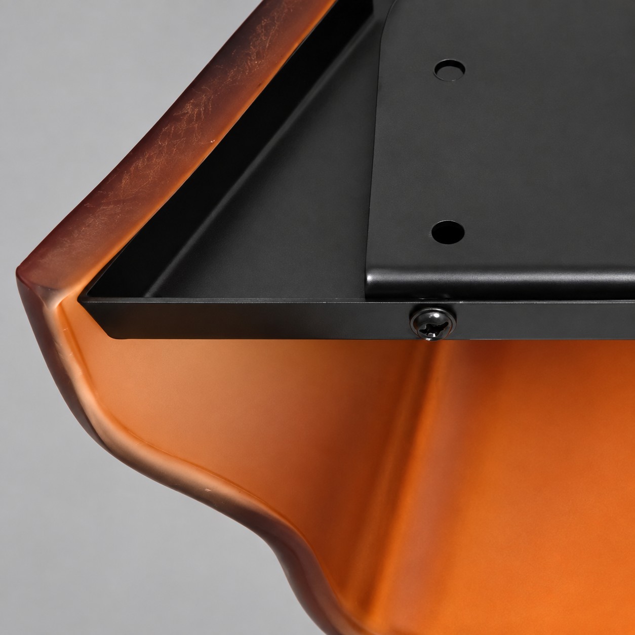 Black metal mounting plate screwed inside the amber glass cup